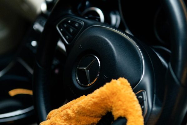 A person cleaning a car with a yellow cloth